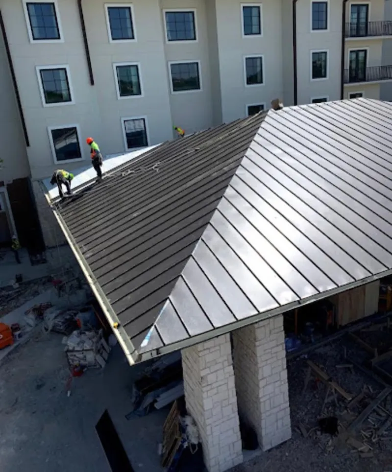 Crew installing standing seam metal roof panels on a commercial project in Lake Zurich